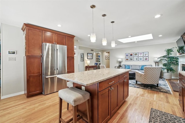 kitchen featuring light wood-style floors, open floor plan, decorative light fixtures, high end refrigerator, and a skylight