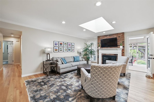 living area with baseboards, recessed lighting, a fireplace, wood finished floors, and a skylight