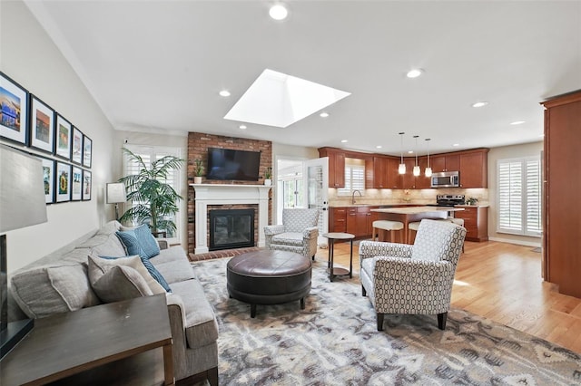 living area with a fireplace, recessed lighting, light wood finished floors, and a skylight