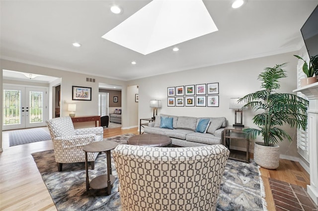living area with visible vents, wood finished floors, ornamental molding, and french doors