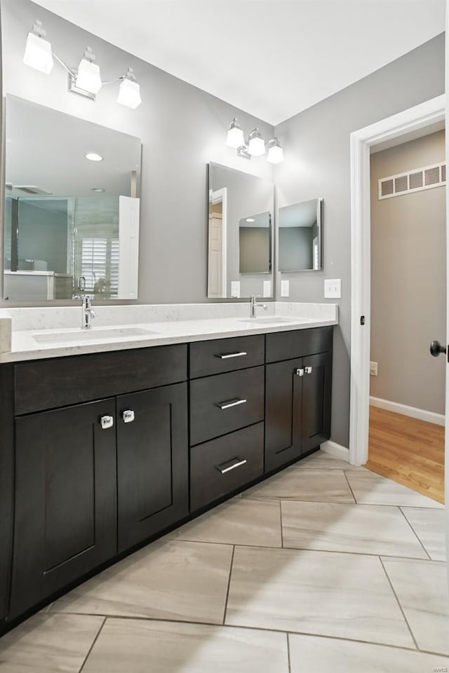 bathroom featuring baseboards, visible vents, double vanity, and a sink