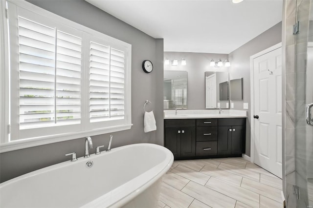full bath with a stall shower, double vanity, a sink, and a soaking tub