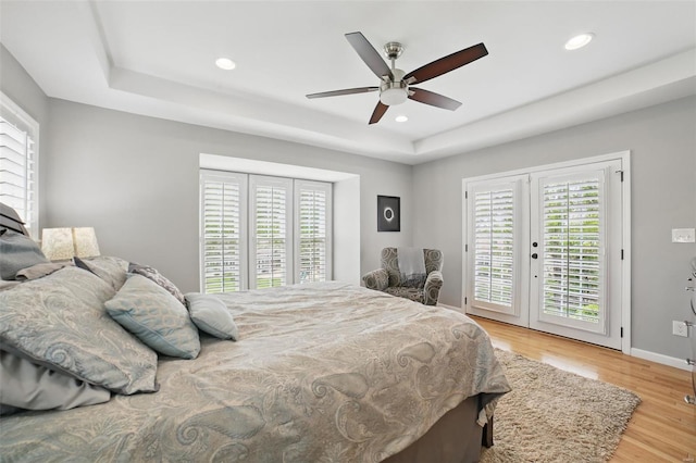 bedroom with multiple windows, access to outside, french doors, and a tray ceiling