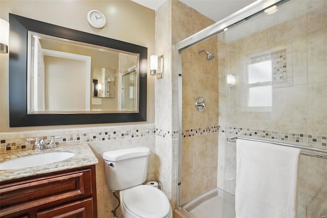 bathroom featuring tile walls, a stall shower, toilet, and vanity