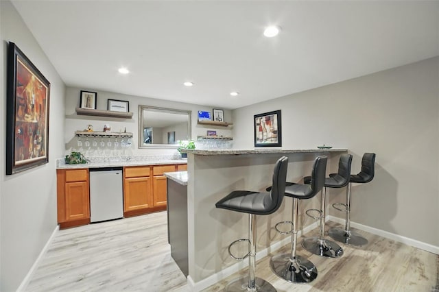 bar featuring light wood-style floors, recessed lighting, indoor wet bar, and baseboards