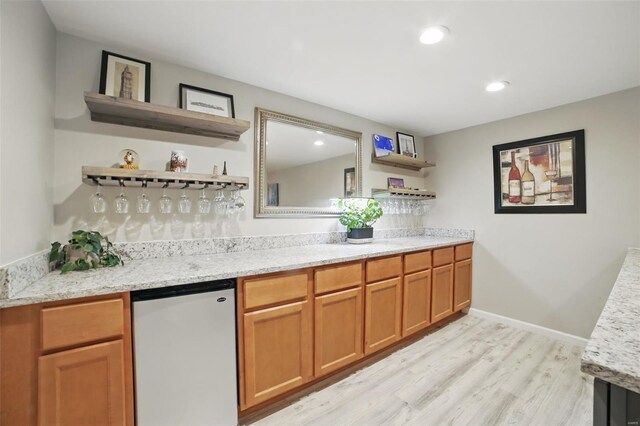 bar featuring recessed lighting, a bar, light wood-style floors, baseboards, and refrigerator