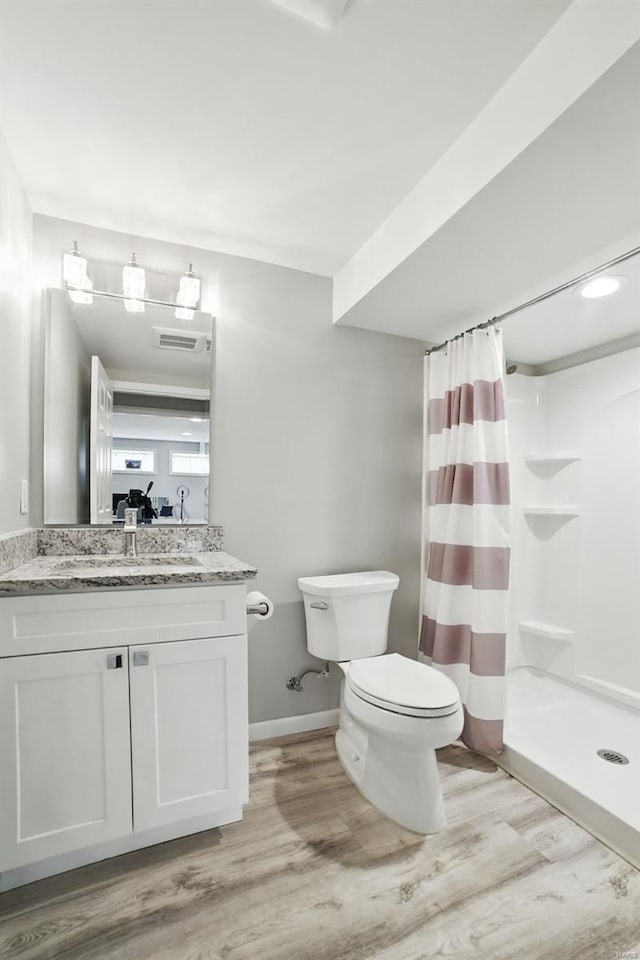 bathroom with a shower stall, vanity, toilet, visible vents, and wood finished floors