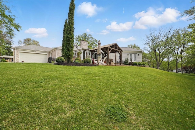 view of front of property with a garage, a gazebo, a chimney, and a front lawn