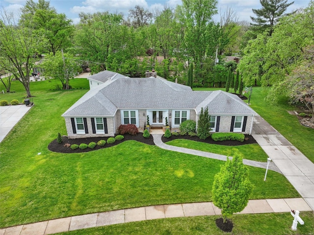 single story home with brick siding, a front lawn, and roof with shingles