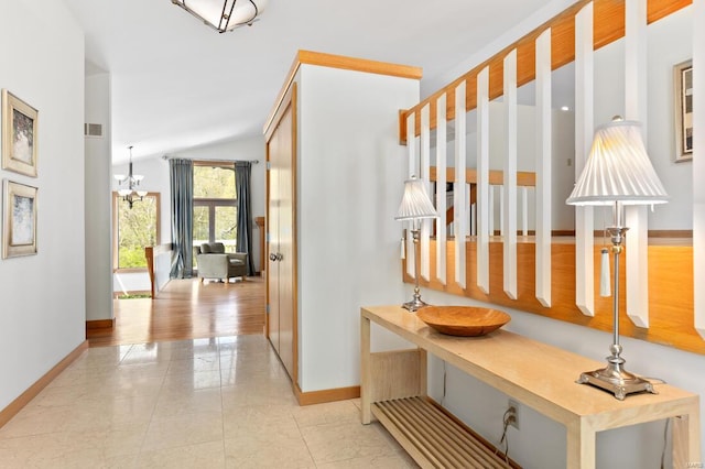 hallway featuring vaulted ceiling, visible vents, baseboards, and an inviting chandelier
