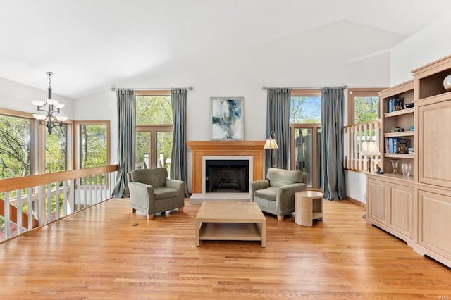 living room featuring a chandelier, light wood-style flooring, a fireplace, and high vaulted ceiling