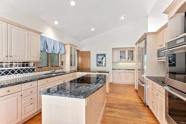kitchen with lofted ceiling, a sink, light wood-style floors, a kitchen island, and appliances with stainless steel finishes