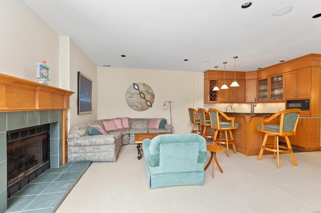 carpeted living area featuring a tiled fireplace