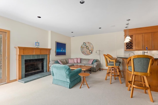 living room with baseboards, a tile fireplace, and light colored carpet