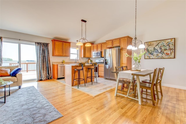 dining space featuring light wood finished floors, vaulted ceiling, baseboards, and a chandelier
