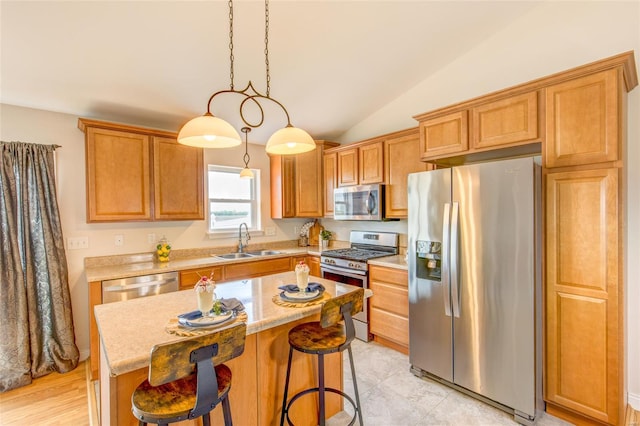 kitchen with a sink, vaulted ceiling, a breakfast bar, a kitchen island, and appliances with stainless steel finishes