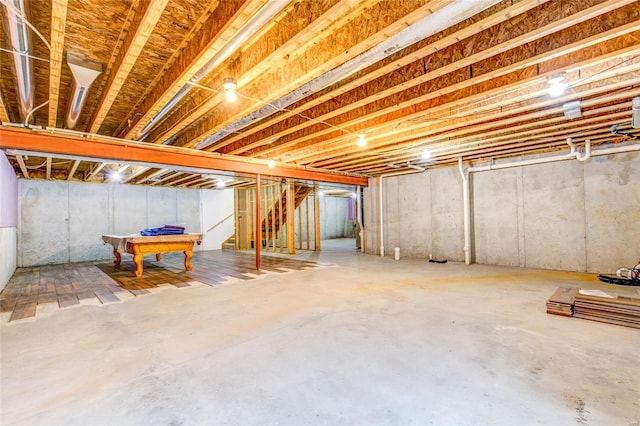 unfinished basement with stairs and pool table