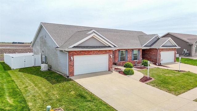 view of front of home featuring driveway, fence, brick siding, an attached garage, and a front yard