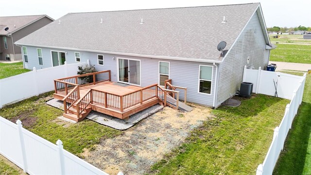 back of property featuring a fenced backyard, a yard, central air condition unit, roof with shingles, and a deck