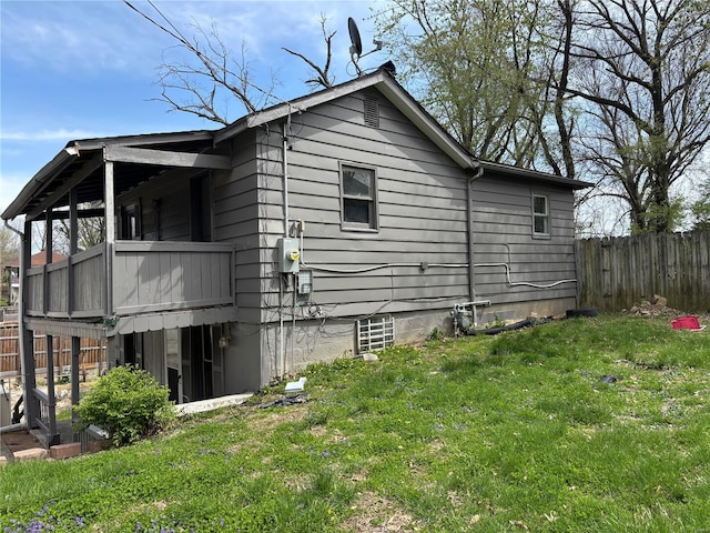 view of property exterior with fence, a lawn, and a balcony