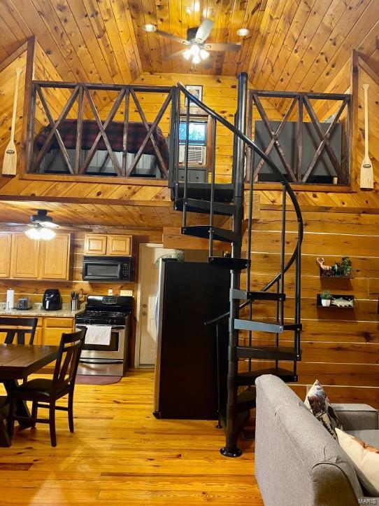 kitchen with black microwave, stainless steel range with gas stovetop, wood walls, and freestanding refrigerator