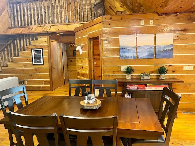dining space with light wood-style flooring and wood walls