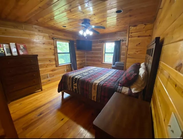 bedroom with wooden ceiling, hardwood / wood-style flooring, multiple windows, and wood walls