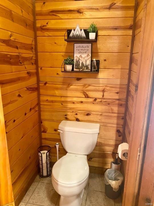 half bath featuring toilet and wood walls