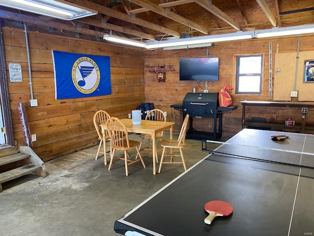 game room featuring wood walls and concrete floors