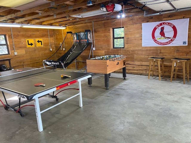 playroom featuring wooden walls, concrete floors, and a garage