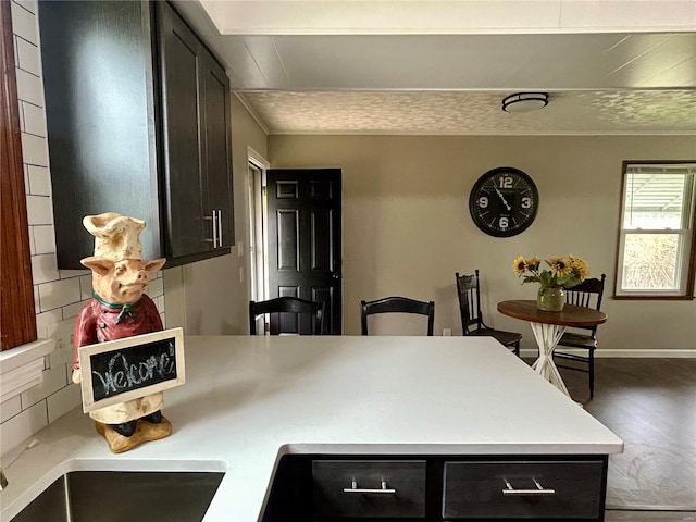 kitchen with a peninsula, dark cabinets, crown molding, and light countertops