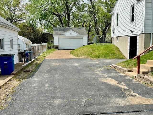 exterior space with fence, an outbuilding, and a detached garage