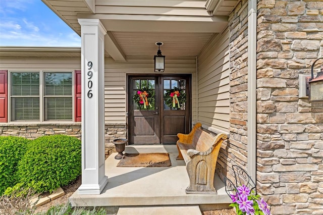 entrance to property with a porch and stone siding