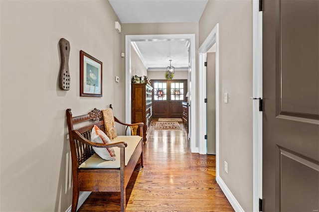 hall featuring ornamental molding, baseboards, and light wood-type flooring