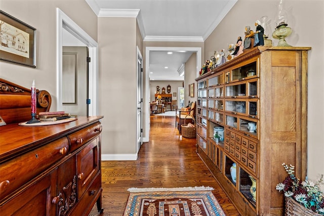 hall featuring dark wood-type flooring, crown molding, and baseboards