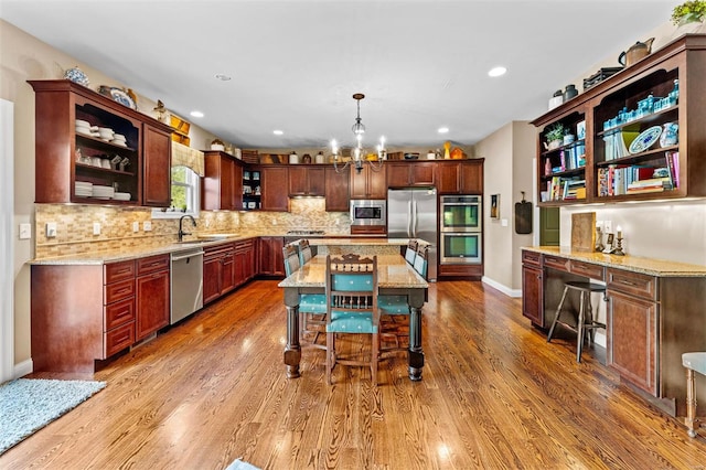 kitchen featuring open shelves, light stone counters, appliances with stainless steel finishes, and a sink
