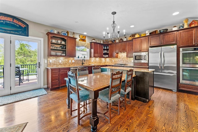 kitchen featuring appliances with stainless steel finishes, a wealth of natural light, an inviting chandelier, and light stone counters