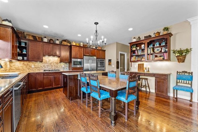 kitchen featuring an inviting chandelier, light stone counters, stainless steel appliances, open shelves, and dark wood-style flooring