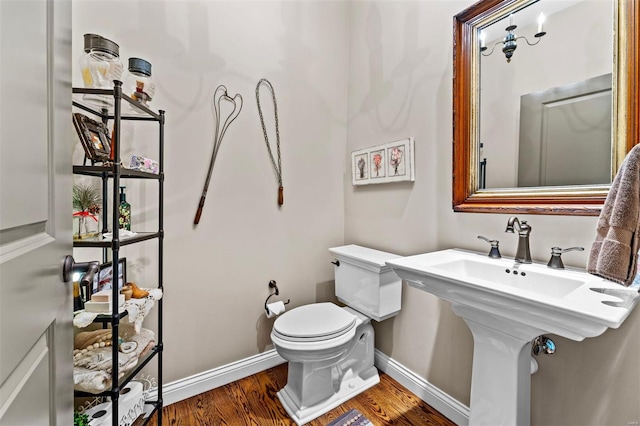 bathroom with toilet, wood finished floors, and baseboards