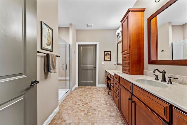 full bathroom featuring visible vents, vanity, a stall shower, and baseboards