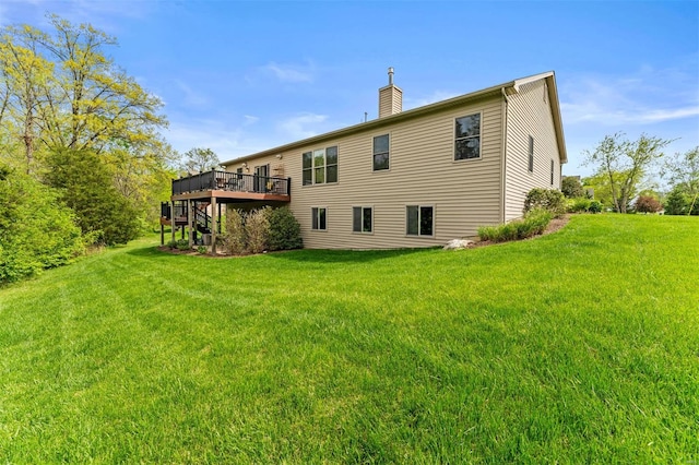 rear view of house with a deck, a yard, and a chimney