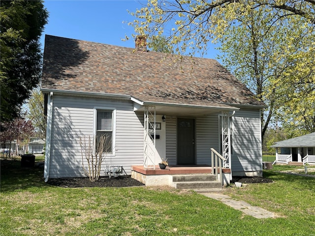 view of front of house featuring roof with shingles, a chimney, and a front yard