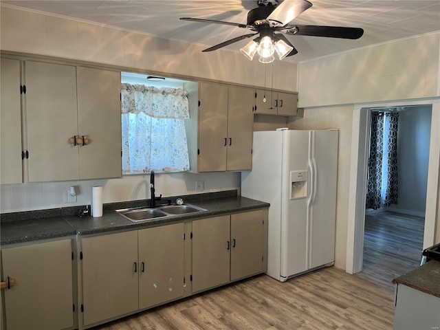 kitchen with dark countertops, white refrigerator with ice dispenser, and a sink