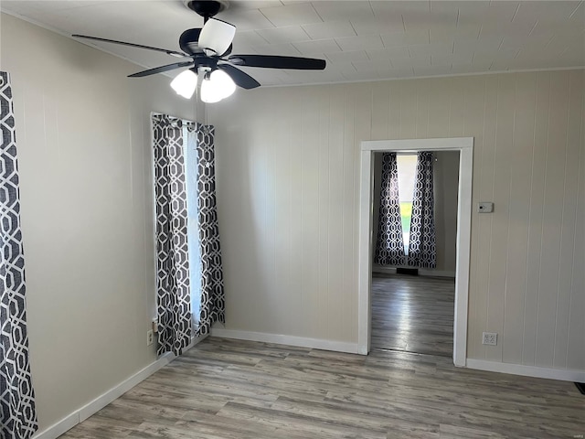 unfurnished room featuring ornamental molding, baseboards, a ceiling fan, and wood finished floors