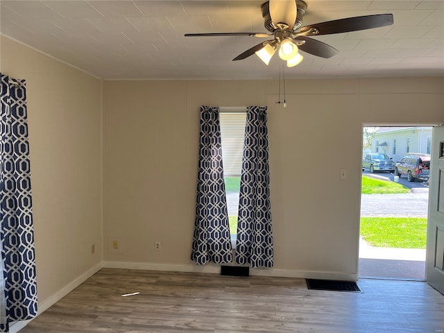 spare room featuring baseboards, wood finished floors, and ceiling fan