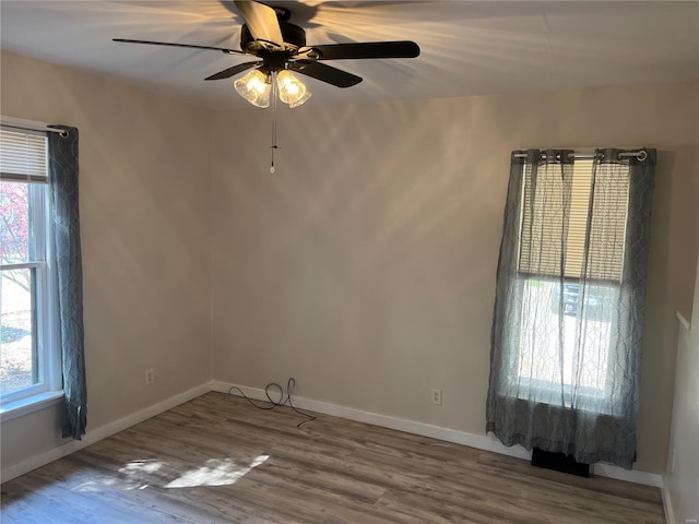 spare room featuring wood finished floors, a wealth of natural light, and ceiling fan