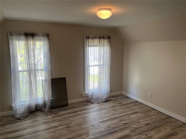 additional living space featuring lofted ceiling, baseboards, and wood finished floors