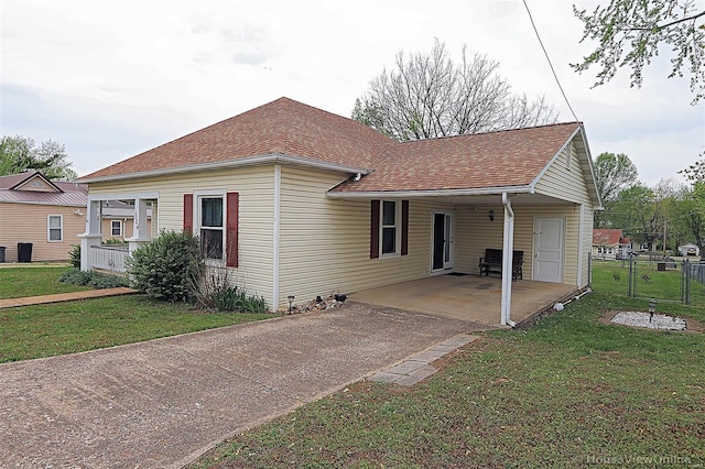 exterior space featuring roof with shingles, a carport, driveway, fence, and a yard