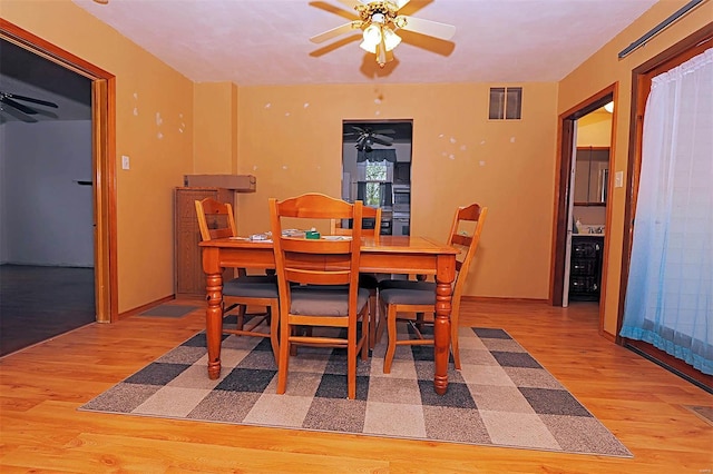 dining area with wood finished floors, baseboards, a ceiling fan, and visible vents