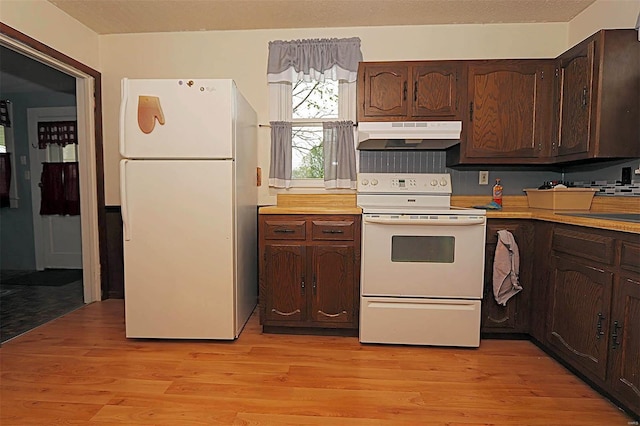 kitchen with dark brown cabinets, light wood-type flooring, white appliances, light countertops, and under cabinet range hood